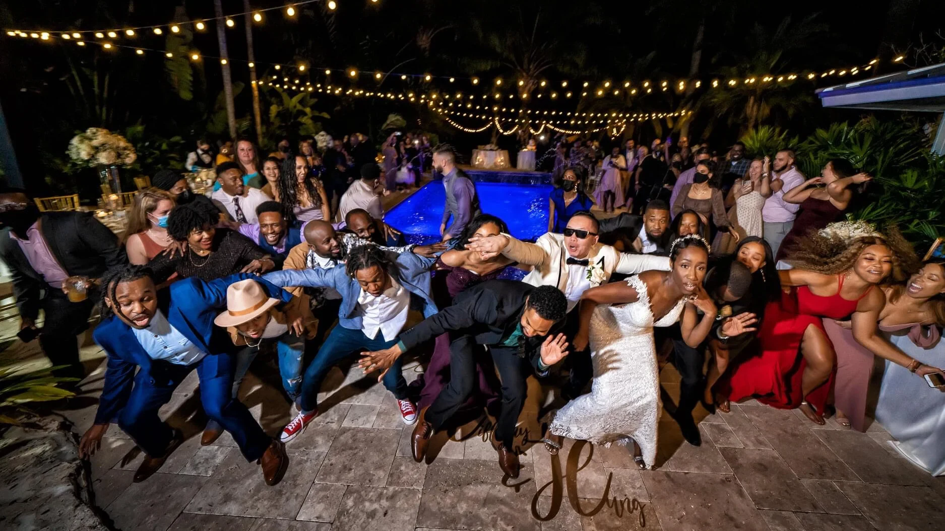 Wedding guests celebrating together on the dance floor beneath string lights.